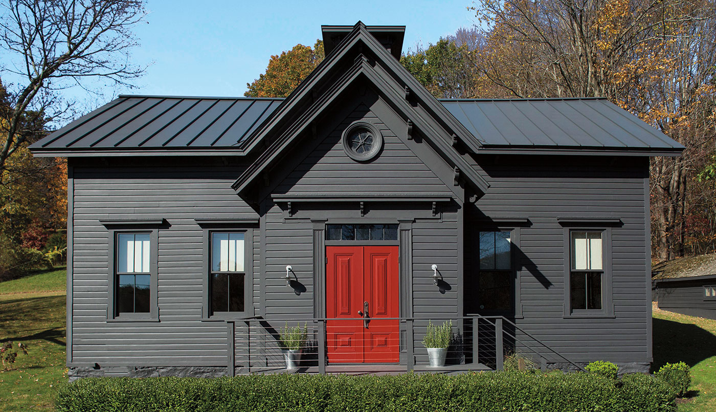 A home with a dark red-painted front door adds a pop of color to a gray-black-painted exterior.