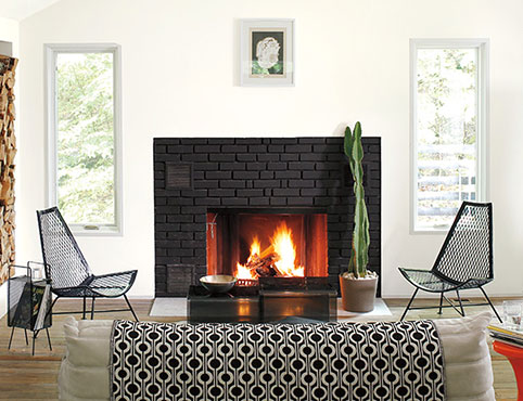 A white-painted living room with a black-framed door, modern black, white and red decor, and a fireplace.