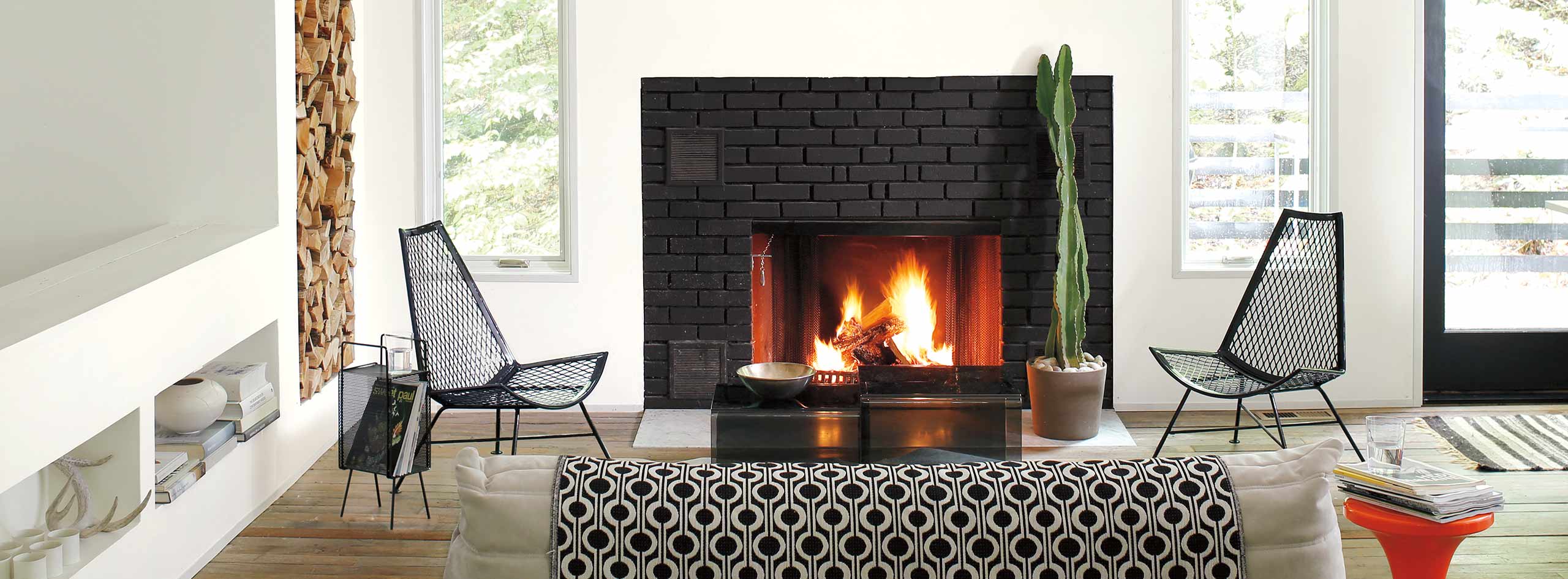 A white-painted living room with a black-framed door, modern black, white and red decor, and a fireplace.