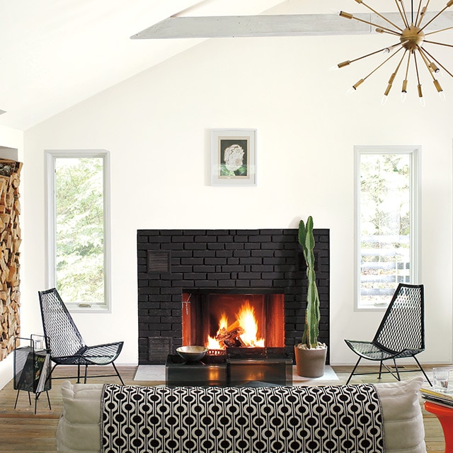 A white-painted living room with a black-framed door, modern black, white and red decor, and a fireplace.