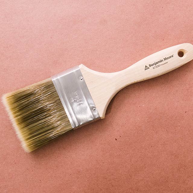 A premium quality Benjamin Moore paintbrush used for painting a garage door.