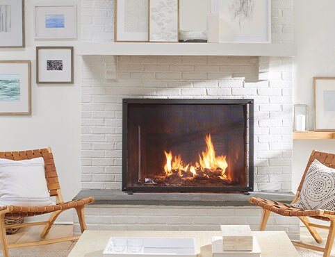 A white painted brick fireplace flanked by matching wooden chairs.