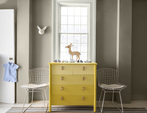 Commode jaune soleil dans une chambre d’enfant grise.