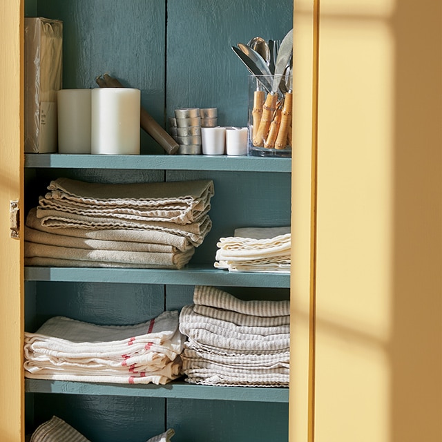 Une armoire ouverte est peinte en Caramel Écossais HC-9 et Vert Antique 2136-40.