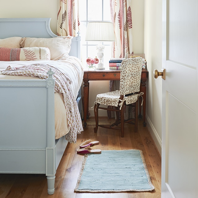 A bedroom with Swiss Coffee painted walls and a blue painted bed frame.