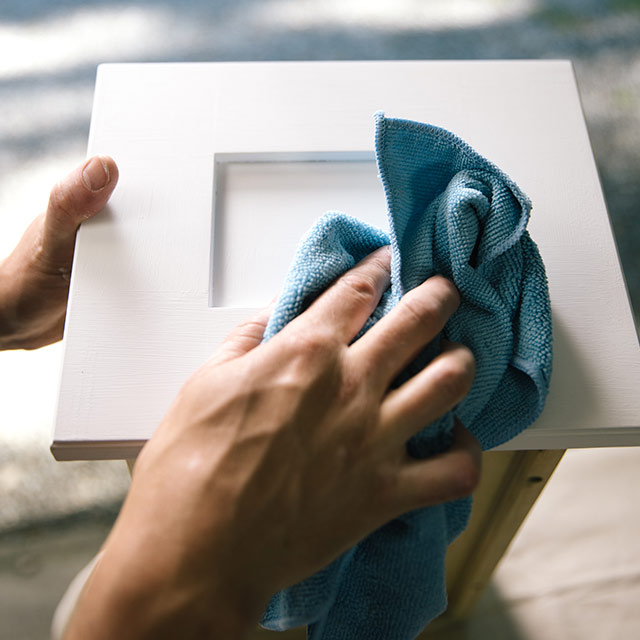 Cleaning surface of bathroom vanity with a microfibre towel.