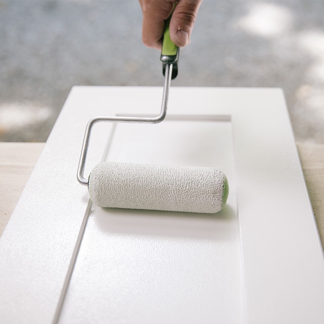 Applying primer to the bathroom vanity cabinet with a roller. 