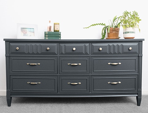 Close up of a green painted cabinet with gold pull handles and knobs.