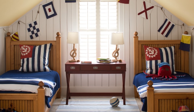 Une chambre à coucher de style marin avec des murs blancs en bois avec feuillures et deux lits jumeaux.