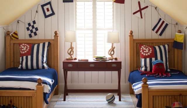 Nautical bedroom with white shiplap walls and two twin size beds.