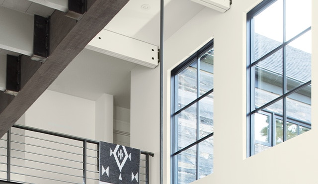 A close up of a building with white walls and black trim, focusing on the high walls above stairs.