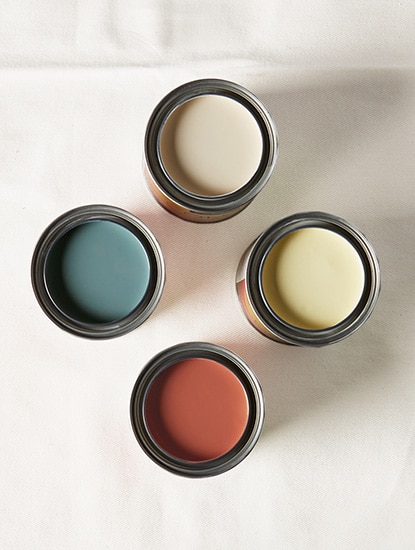 Four paint colour samples with lids off, showcasing a range of paint colours inside.