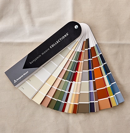 Un muestrario abanico de Benjamin Moore apoyado sobre una mesa con la Colección de blancos impuros, los clásicos de diseñador y otras. Un muestrario abanico de Benjamin Moore apoyado sobre una mesa con la Colección de blancos impuros, los clásicos de diseñador y otras.