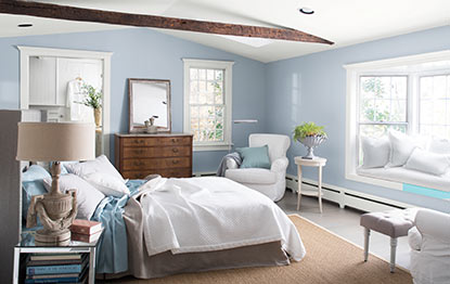 Bright bedroom with light blue walls and an exposed wood beam