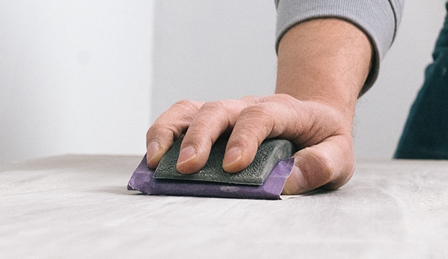A person sanding a piece of furniture.