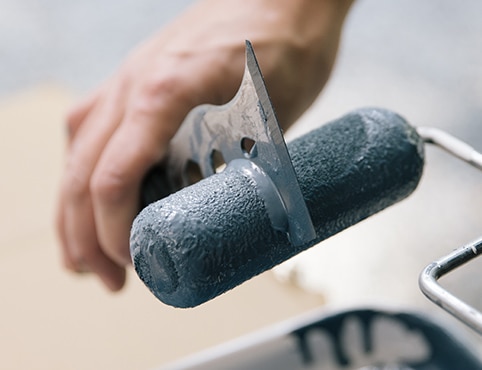 Cleaning paint roller with a scraper.