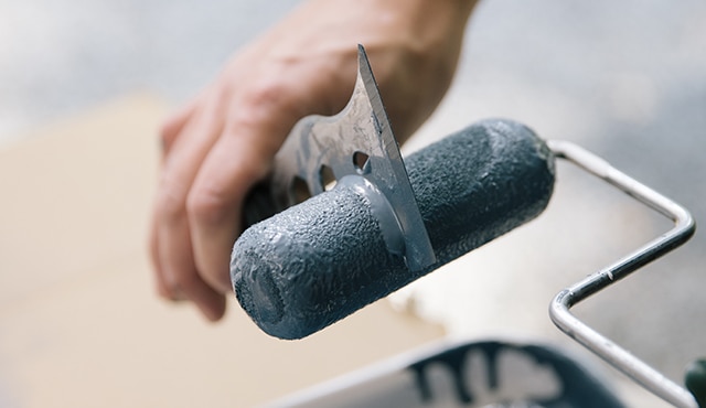 Cleaning paint roller with a scraper.