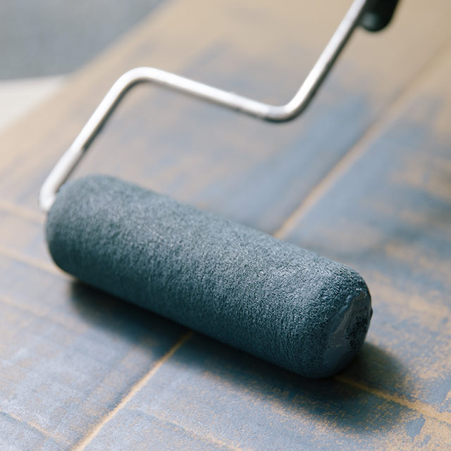 A paint roller being cleaned on a box.