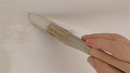 Un entrepreneur en peinture découpe la ligne du plafond d’une pièce