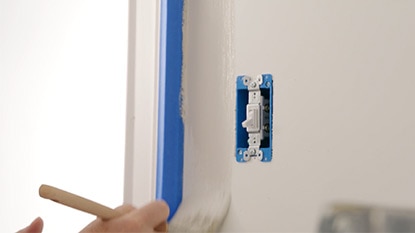 Painting contractor cutting in paint around a light switch