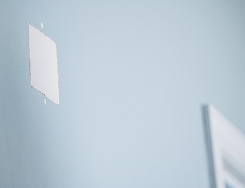 A blue wall with a square patch from fixing a hole in the wall.