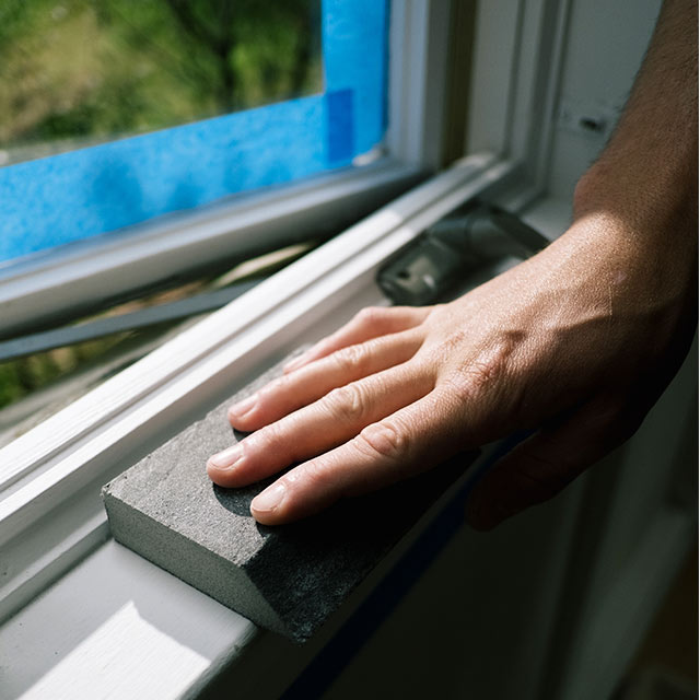 Un dueño de casa lijando un marco de ventana. Un dueño de casa lijando un marco de ventana.