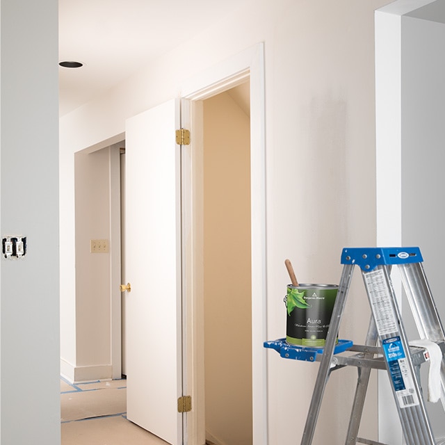 Open can of Benjamin Moore® Aura® white interior paint is resting on a ladder.