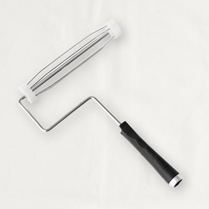 A metal paint roller frame with a black handle.