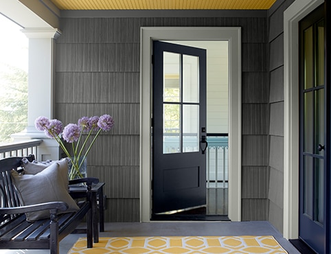 A gray porch with white trim, blue doors and a striking yellow ceiling.