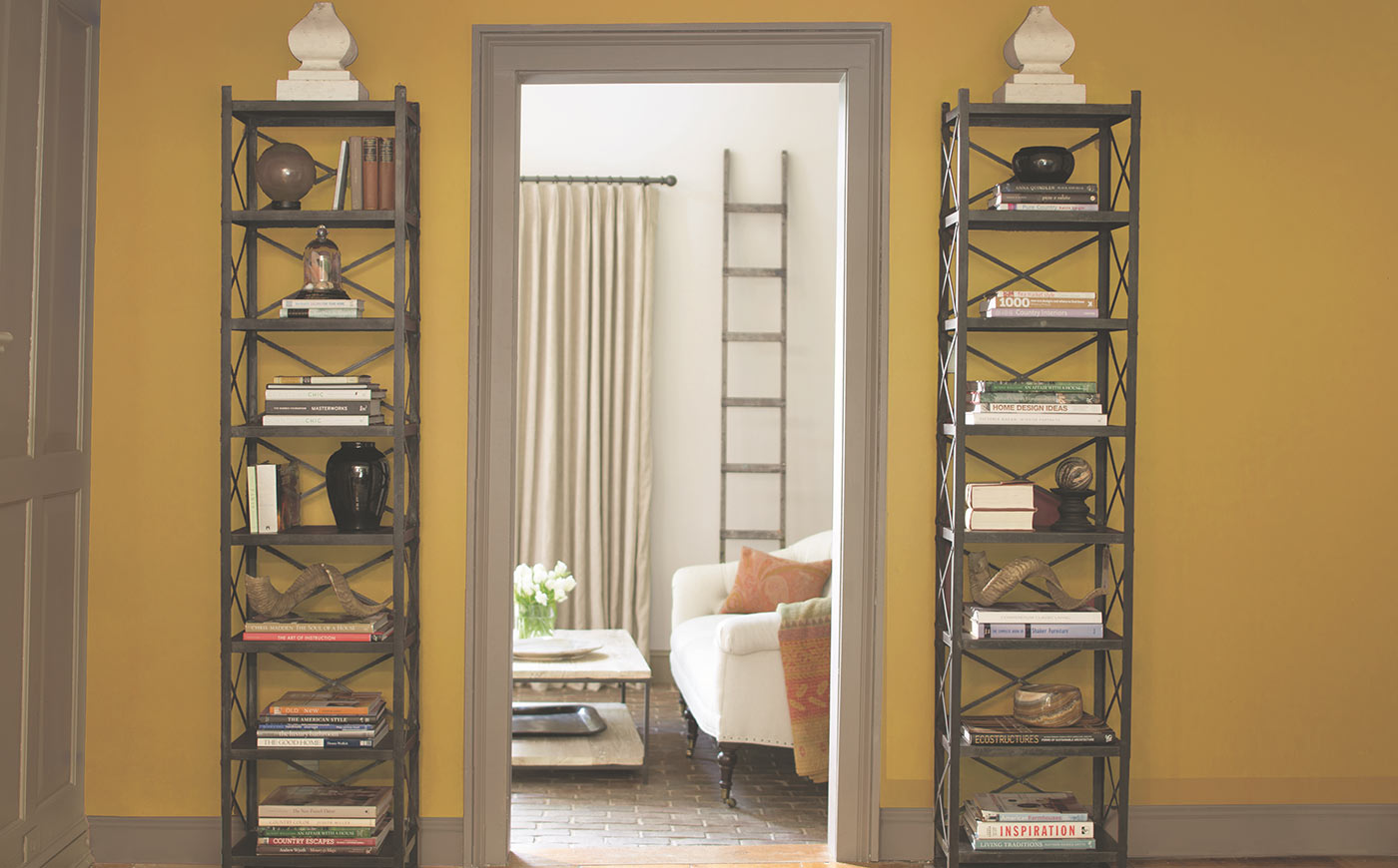 Yellow walls with a gray trim hallway frame leading to a white cozy living room.