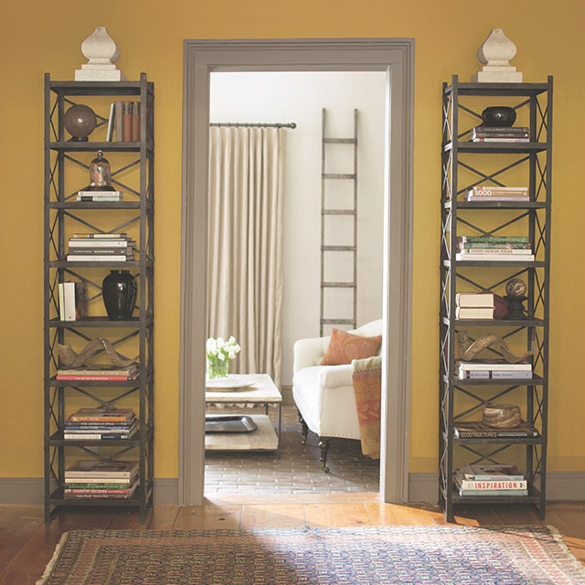 Yellow walls with a gray trim hallway frame leading to a white cozy living room.