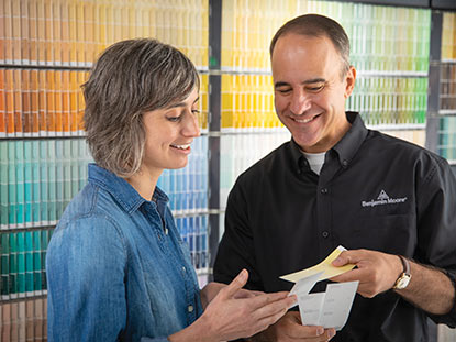 A Benjamin Moore Representative Helping a Customer Select Different Color Paint Sample Cards.