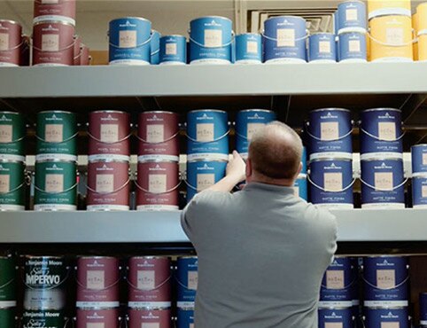 Man selecting from various Benjamin Moore paint cans