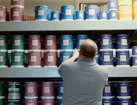 Man selecting from various Benjamin Moore paint cans Man selecting from various Benjamin Moore paint cans