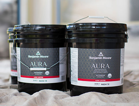 Five gallon pails of AURA® Exterior Paint set on top of a drop cloth.