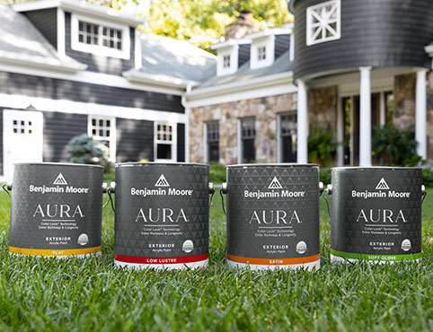 Four gallons of AURA® Exterior paint on a front lawn.