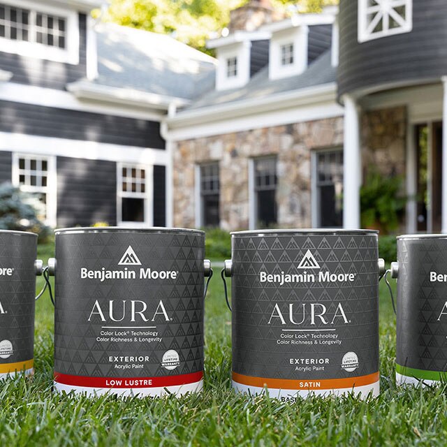 Four gallons of AURA® Exterior paint on a front lawn.