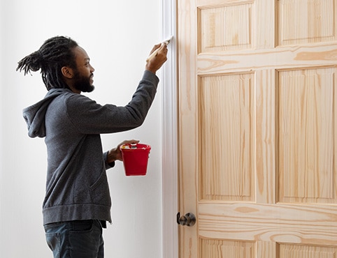 A person uses Fresh Start® primer on trim around a door.