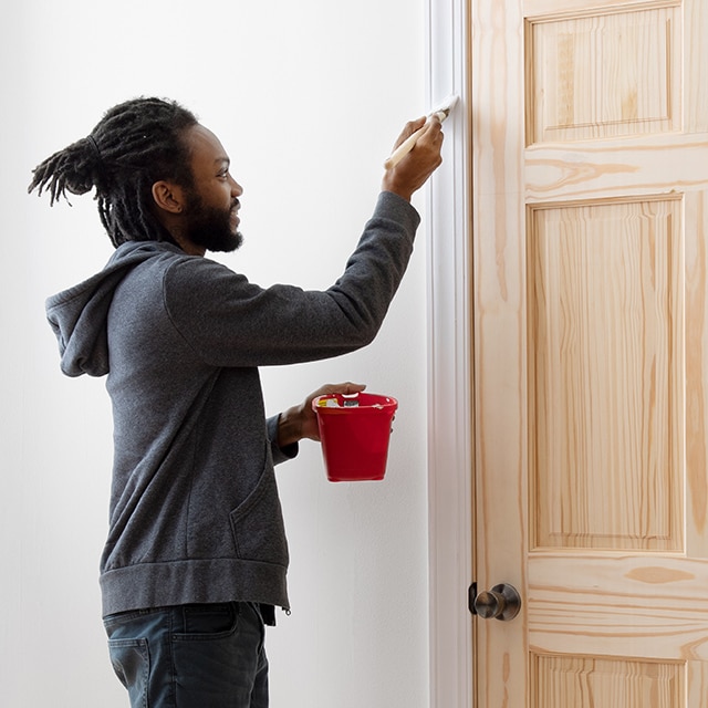 A person uses Fresh Start® primer on trim around a door.