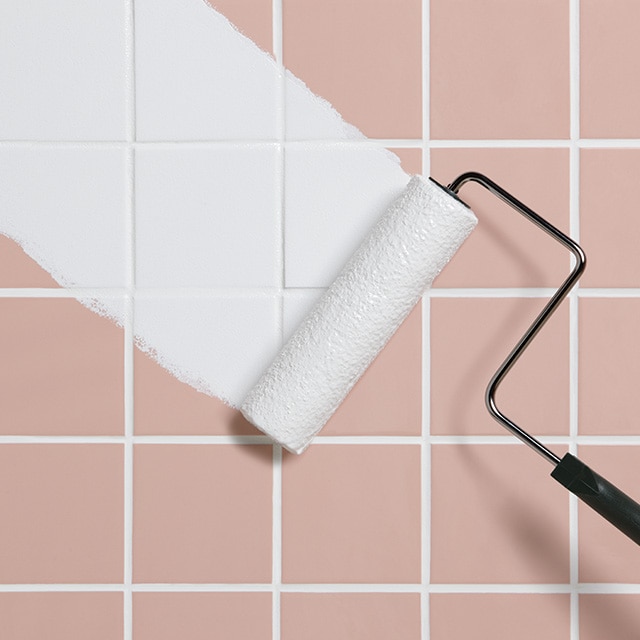 Paint roller painting over bathroom tile.