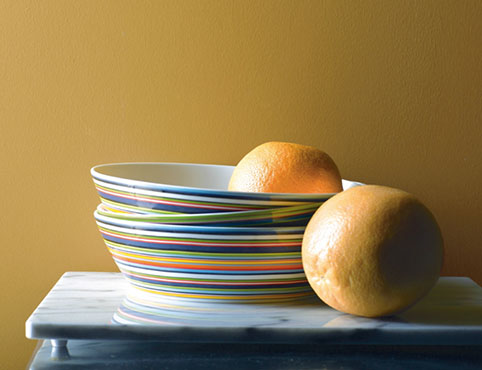 Des assiettes dans une variété de couleurs vives contre un mur jaune