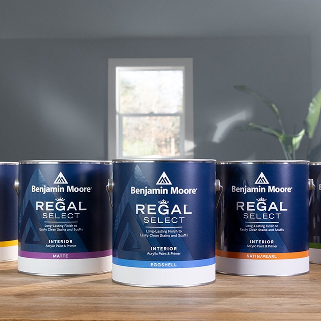 Cans of Regal Select Interior Paint on a wood tabletop.