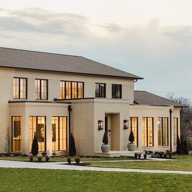 A home exterior painted a neutral yellow-brown with tall windows.