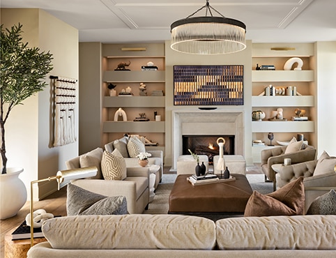A large living room with painted off-white walls, a white paint ceiling, and recessed shelving, with furniture and decorations framing a fireplace.