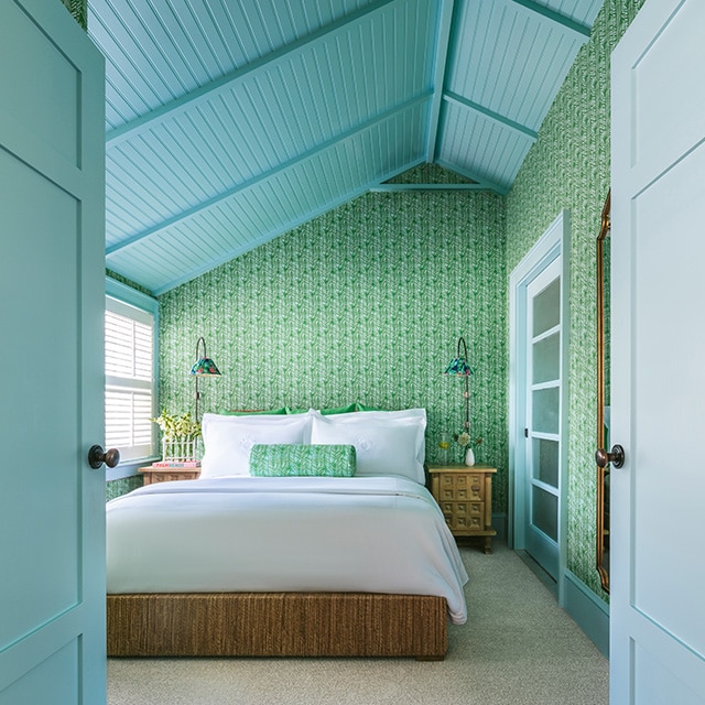 Una habitación con techo abovedado con revestimiento pintado en color azul cielo, marcos y puertas a juego, y papel pintado con un encantador diseño verde.