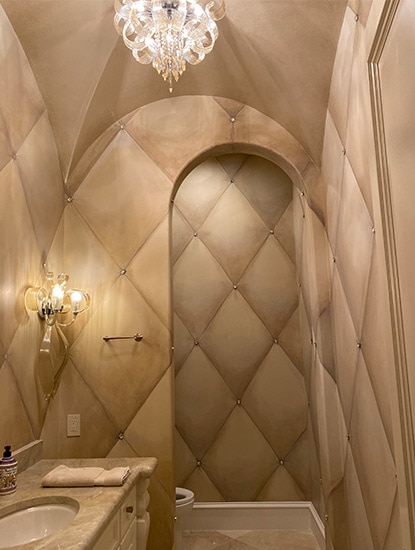 An elegant bathroom with high ceilings and tan walls featuring a billowing diamond design.