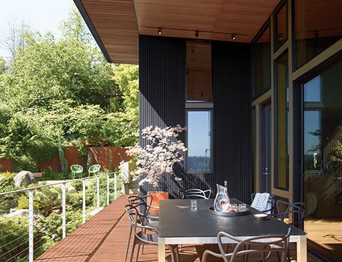 House with black siding and brown deck.