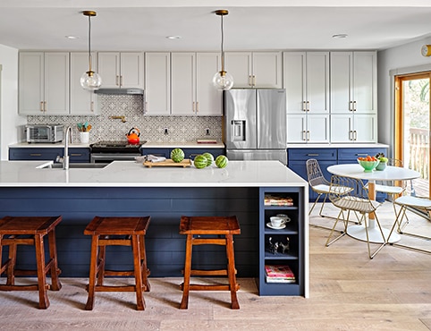 After photo of a large repainted two-toned kitchen featuring gray upper cabinets and navy blue lower cabinets with a matching blue island.