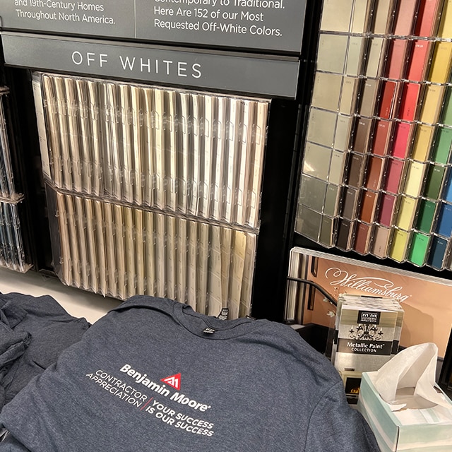 Benjamin Moore tee shirts in front of paint color chip strips shown in a display seen in a locally owned Benjamin Moore store.