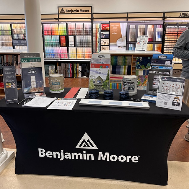 Une table de présentation arborant des brochures Benjamin Moore, des contenants de peinture et des échantillons de couleurs dans un magasin local Benjamin Moore.